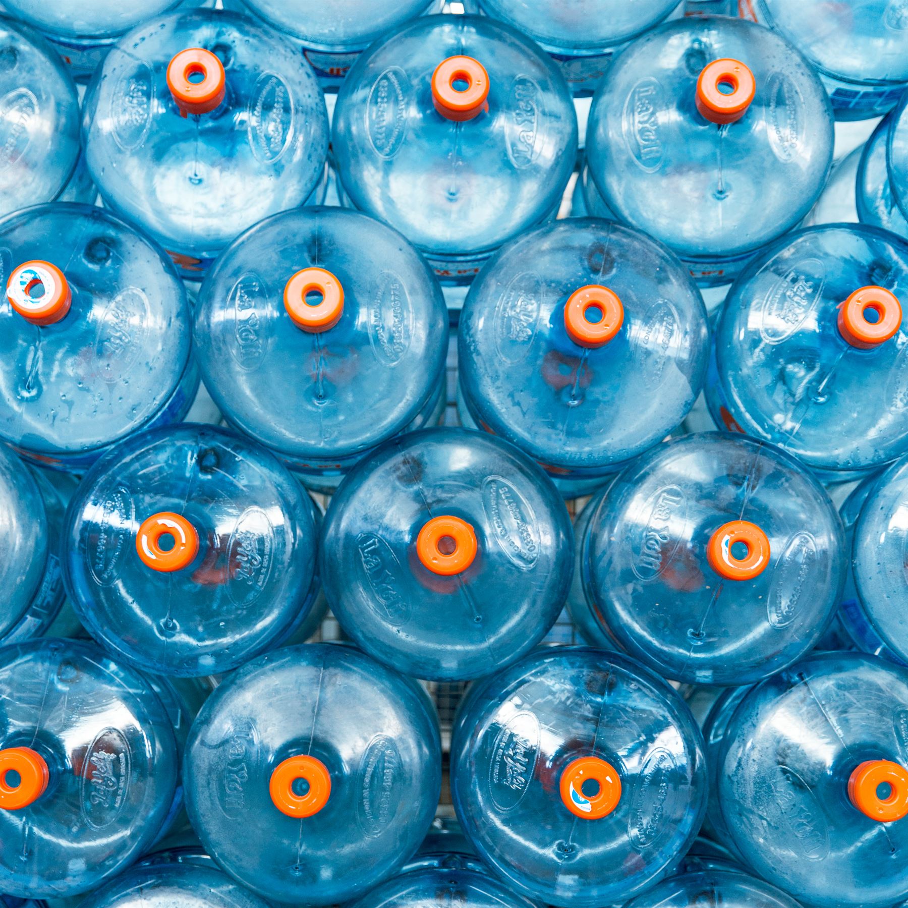 Bidones de agua apilados en pallets, listos para el reparto